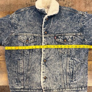 Puede incluir: Chaqueta vaquera azul con cuello y forro de borreguillo blanco. La chaqueta tiene dos bolsillos en el pecho y dos bolsillos laterales. La chaqueta mide unos 61 cm de ancho en el pecho.