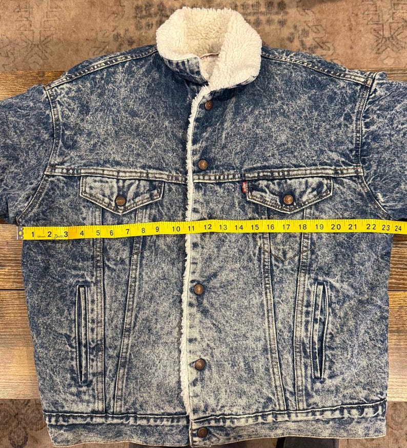 Puede incluir: Chaqueta vaquera azul con cuello y forro de borreguillo blanco. La chaqueta tiene dos bolsillos en el pecho y dos bolsillos laterales. La chaqueta mide unos 61 cm de ancho en el pecho.