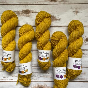 以下が含まれることがあります： 白いラベルに「Forage & Sow Dye Works」と書かれた、黄色の糸の巻き糸が5つあります。