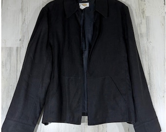 May include: A black jacket with a pointed collar, long sleeves, and two front pockets. The jacket features a front opening, a visible inner lining, and a brand label at the neckline. The fabric has a textured appearance and a solid black color.