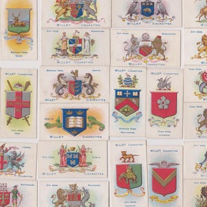 Könnte beinhalten: Eine Sammlung von Sammelkarten von Wills's Cigarettes mit verschiedenen Stadtwappen. Die Karten zeigen farbenfrohe heraldische Designs mit Wappen, Wappen und Text. Die Karten sind rechteckig und haben eine Vintage-Ästhetik.