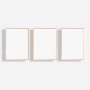 May include: Three empty picture frames with light wood frames. The frames are arranged horizontally in a row.
