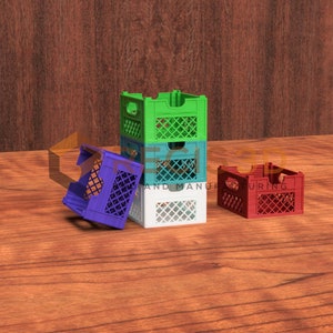 Puede incluir: Un conjunto de cuatro pequeñas cajas en verde, azul, blanco y rojo. Una caja azul está volcada. Las cajas tienen un diseño de celosía y están sobre una superficie de madera. Adecuado para fines decorativos.