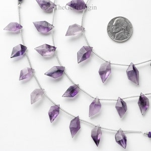 May include: A strand of amethyst gemstone beads, each bead is faceted and shaped like a diamond. The beads are strung on a silver wire and are approximately 1/2 inch in length. The beads are a light purple color and have a slight shimmer to them.