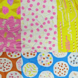 Pu&ograve; includere: Una trapunta patchwork con una variet&agrave; di motivi colorati. La trapunta presenta quadrati con disegni tra cui ciliegie rosa su bianco, caramelle rosa e coni gelato su giallo. La trapunta &egrave; cucita con filo blu.