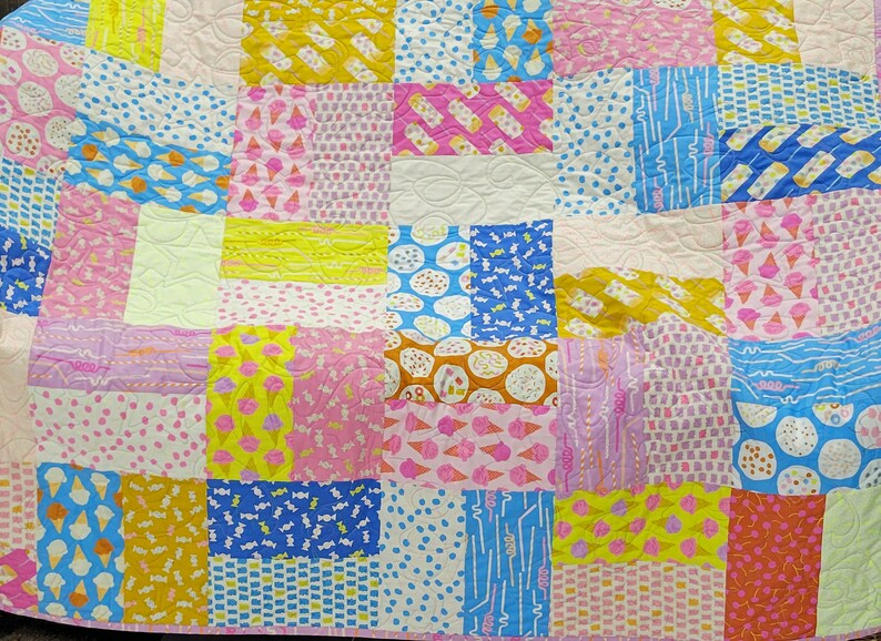 Pu&ograve; includere: Una colorata trapunta patchwork con vari quadrati a fantasia. La trapunta presenta coni gelato, caramelle e pois nei toni del rosa, giallo, blu e arancione. &Egrave; un articolo fatto a mano e accogliente.