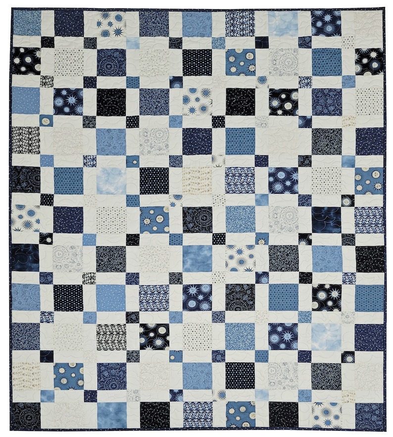 May include: A patchwork quilt in shades of blue, white, and black. The quilt features a grid pattern of squares in various sizes and patterns, including polka dots, floral designs, and solid colors. The overall design is symmetrical and visually appealing.