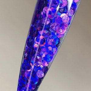 May include: A clear nail polish bottle filled with iridescent blue and purple glitter.
