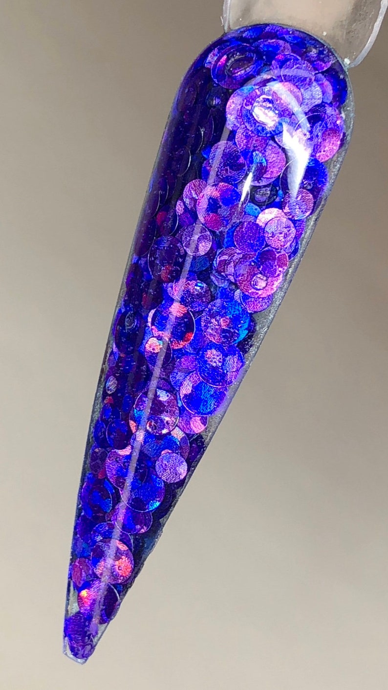 May include: A clear nail polish bottle filled with iridescent blue and purple glitter.