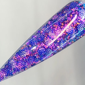 May include: A clear nail polish bottle with a holographic glitter finish. The glitter is a mix of blue, pink, and purple.