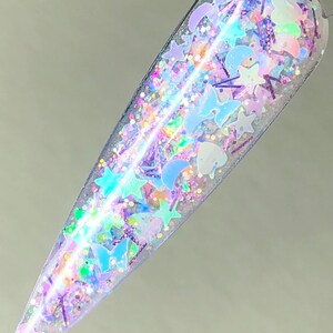 May include: A clear nail polish bottle filled with iridescent glitter in various shapes, including stars, butterflies, and moons.