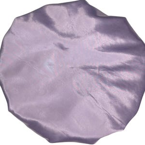 Op de afbeelding: Een slaapmuts van lavendel satijn. De muts is gemaakt van zacht, glad satijn en is ontworpen om haar te beschermen tegen breuk en pluis.