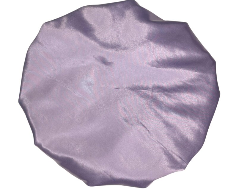 Op de afbeelding: Een slaapmuts van lavendel satijn. De muts is gemaakt van zacht, glad satijn en is ontworpen om haar te beschermen tegen breuk en pluis.