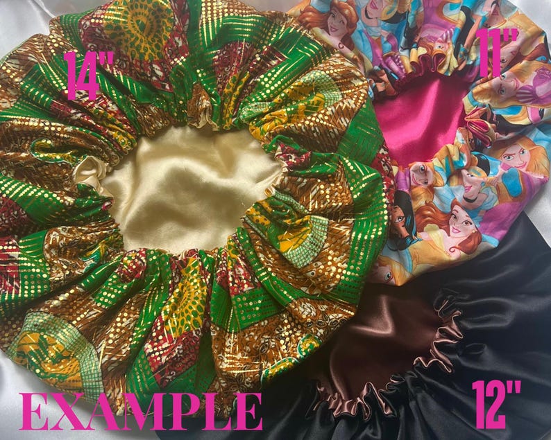 Op de afbeelding: Drie satijnen bonnets in verschillende patronen en kleuren. De eerste bonnet is groen en goud met een diameter van 14 inch. De tweede bonnet is roze met een prinsessen-thema en een diameter van 11 inch. De derde bonnet is zwart met een diameter van 12 inch.