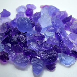 May include: A collection of purple and blue amethyst crystals of various sizes and shapes. The crystals are rough and have a natural, unpolished look.