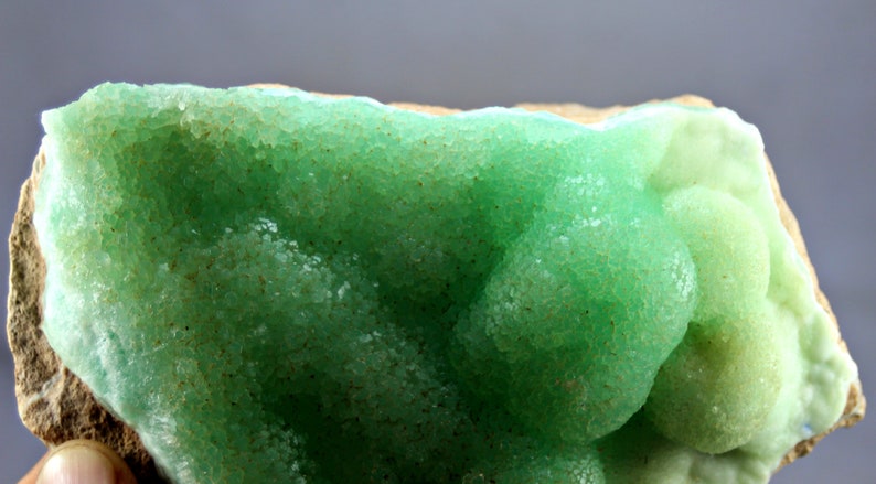 May include: A green and white mineral specimen with a rough, textured surface. The mineral is a geode, which is a hollow rock lined with crystals.