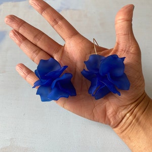 May include: A pair of blue flower-shaped earrings with gold wire hooks.