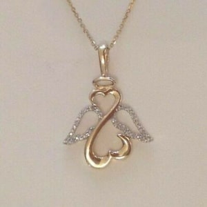 May include: A gold pendant necklace with a heart-shaped design and angel wings. The wings are adorned with small, clear stones.
