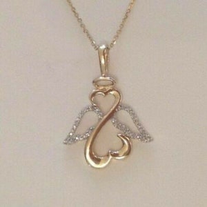 May include: A gold pendant necklace with a heart-shaped design and angel wings. The wings are adorned with small, clear stones.