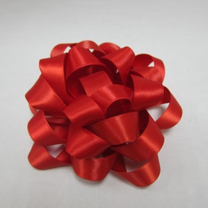 May include: A red satin ribbon bow, tied in a decorative knot, with multiple loops and layers.