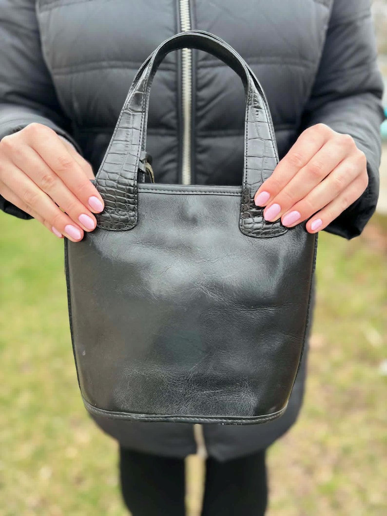 May include: A set of three ceramic mugs with a speckled, matte finish. The mugs are in shades of cream, light gray, and dark gray. Each mug has a simple, minimalist design and a rounded handle.