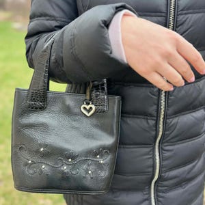 May include: A set of three ceramic mugs with a speckled, cream-colored glaze. Each mug features a different hand-painted floral design in shades of blue, green, and yellow. The mugs have a simple, rounded shape and a comfortable handle.