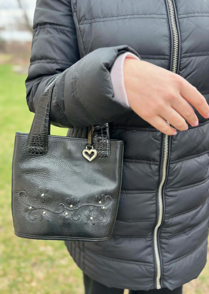 May include: A set of three ceramic mugs with a speckled, cream-colored glaze. Each mug features a different hand-painted floral design in shades of blue, green, and yellow. The mugs have a simple, rounded shape and a comfortable handle.