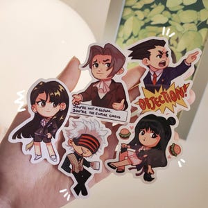 Könnte beinhalten: Eine Sammlung von Aufklebern im Anime-Stil mit Charakteren in verschiedenen Posen. Ein Aufkleber hat das Wort "OBJECTION!" in einem gelben Ausbruch. Ein anderer Aufkleber hat den Text "You're not a clown. You're the entire circus."
