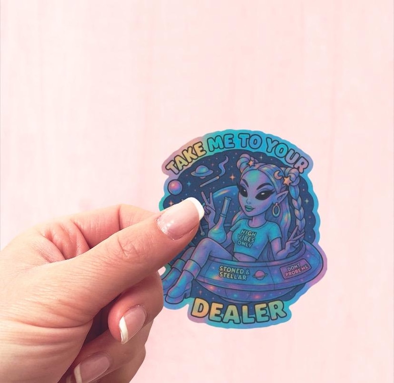 May include: Holographic sticker featuring an alien in a spaceship with the text "Take Me To Your Dealer." The alien has blue skin, long braided hair, and is wearing a shirt that says "High Vibes Only." The sticker has a space-themed background.