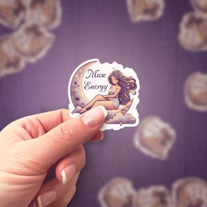 Op de afbeelding: Een sticker met een vrouw met lang, donker haar die op een halve maan zit. De maan is versierd met sterren en de tekst "Muse Energy" is in witte letters geschreven.