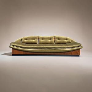 May include: A mid-century modern sofa with a curved, olive green velvet upholstered back and seat. The sofa has three button-tufted back cushions and sits on a wooden base with a dark blue trim. A stylish piece of furniture.