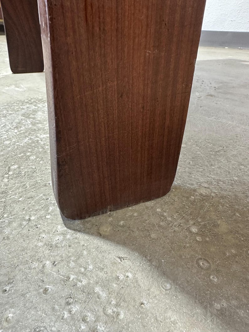 May include: Close-up of the bottom of a dark brown wooden table leg.