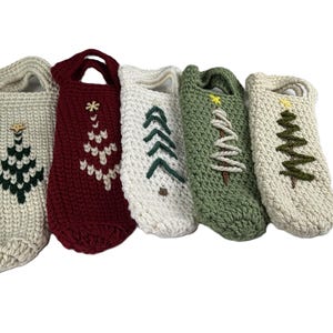 Pu&ograve; includere: Cinque copribottiglie all'uncinetto con manici, ognuno caratterizzato da un diverso disegno di albero di Natale ricamato. Le coperture sono color crema, rosso scuro, bianco, verde salvia e crema, con alberi in filati contrastanti e stelle gialle.