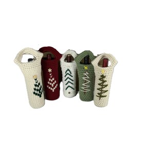 Pu&ograve; includere: Cinque copribottiglie cilindrici all'uncinetto con manici, ognuno caratterizzato da un disegno di albero ricamato. Le coperture sono color crema, rosso scuro e verde salvia, con filati di colori contrastanti per i motivi degli alberi e stelle.