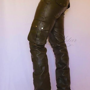 May include: Dark green leather cargo pants with a brown leather belt and brown leather boots. The pants have a large cargo pocket on the left leg.