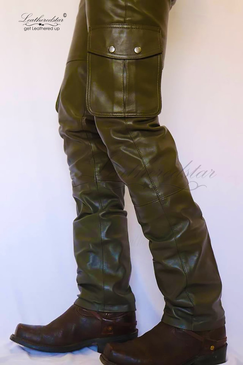 May include: Olive green leather cargo pants with a large cargo pocket on the right leg. The pants are worn with brown cowboy boots.