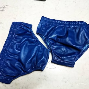 May include: Two pairs of blue leather underwear. The underwear is made of a shiny, smooth leather and has a high-cut leg.