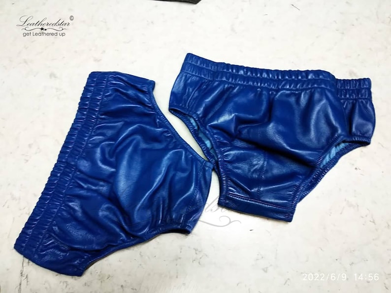 May include: Two pairs of blue leather underwear. The underwear is made of a shiny, smooth leather and has a high-cut leg.