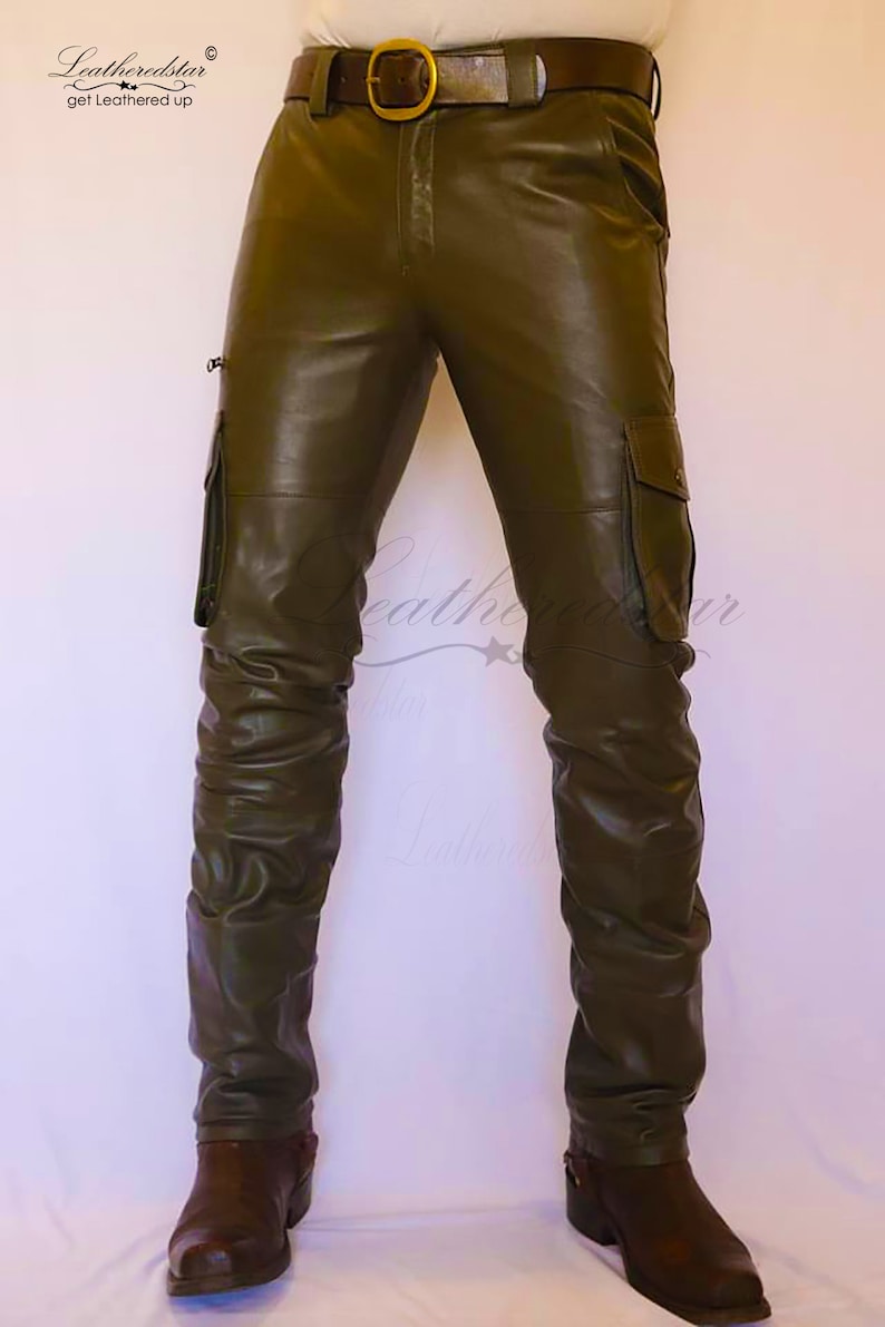 May include: Olive green leather cargo pants with a brown leather belt and brown leather boots. The pants have a zippered pocket on the side and a flap pocket on the thigh.