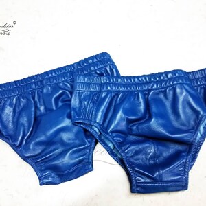 May include: Two pairs of blue leather underwear. The underwear is made of a shiny, smooth leather and has a simple design.
