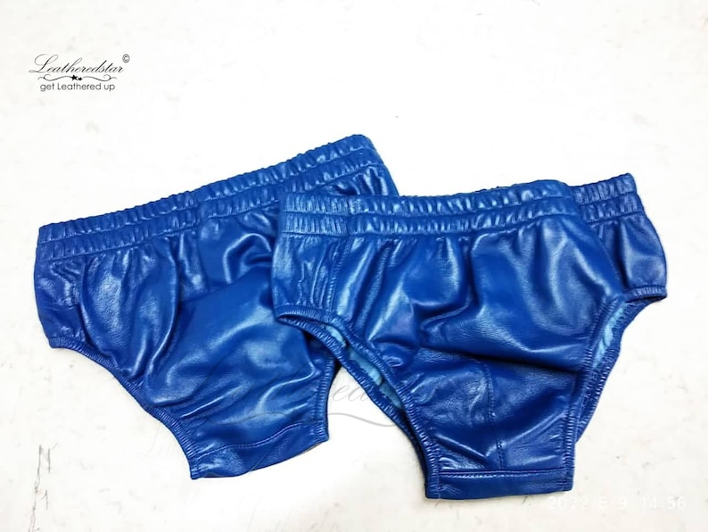 May include: Two pairs of blue leather underwear. The underwear is made of a shiny, smooth leather and has a simple design.
