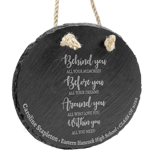 May include: Black round slate plaque with a white rope hanger. The plaque has an inspirational quote engraved on it: "Behind you all your memories, Before you all your dreams, Around you all who love you, Within you all you need". The plaque also has the text "Caroline Stapleton. Eastern Hancock High School. Class of 2022" engraved on it.
