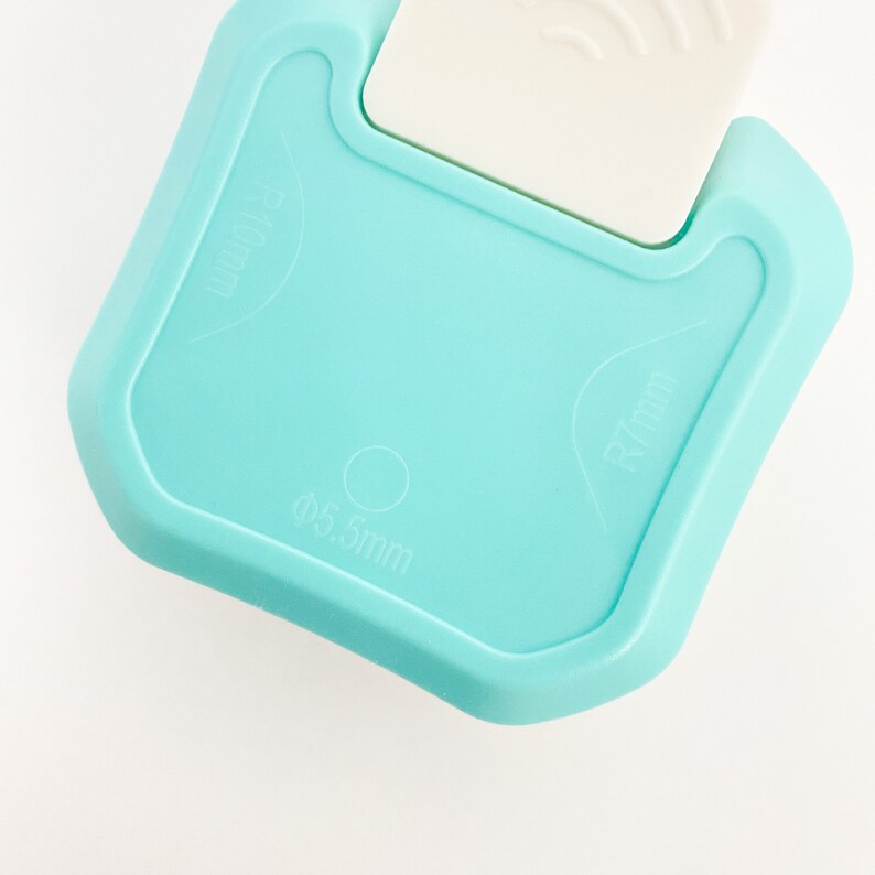 May include: A light blue plastic tool with measurements in millimeters. The tool has a rounded edge and a small circle in the center. The text on the tool reads "R 7mm", "&Oslash; 5.5mm", and "R 40mm".