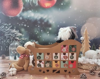 May include: A brown cardboard sleigh-shaped advent calendar with 12 small drawers, each decorated with festive designs. A plush moose with a red and white scarf and a gnome are in the sleigh. The background features Christmas ornaments and a snowy scene.