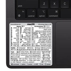 May include: A white rectangular sticker with black text applied to the palm rest of a dark gray laptop. The sticker displays a comprehensive list of macOS keyboard shortcuts, organized into sections like Basics, Screenshots, Desktop, and Recovery.