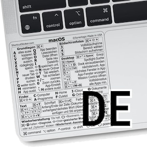 May include: A white sticker with macOS keyboard shortcuts, including commands for Finder, Text, and Desktop functions, is placed on a laptop keyboard. The sticker has the text "ShortcutSticker.com" and the letters "DE" are visible.