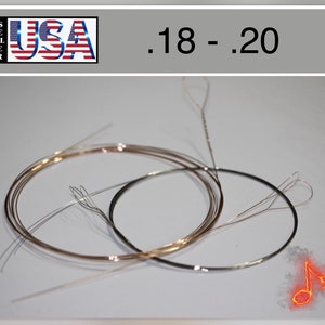 Puede incluir: Varias cuerdas metálicas, probablemente para un instrumento musical, están dispuestas en un patrón circular. Las cuerdas varían en color, algunas parecen plateadas y otras doradas. El texto ".18 - .20" se muestra encima de las cuerdas.