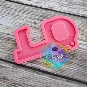 May include: Pink silicone mold shaped like a key with a small circle in the center. The mold is on a woodgrain background. The text "Twisted Willow Craft Supply" is visible in the bottom right corner of the image.