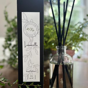 May include: A black box with a white label that says "Cambridge & Carlino Chester, NJ Limoncello Reed Diffuser 8 oz 236 ml" with a drawing of a branch of leaves. A clear glass bottle with black reeds is in front of the box.