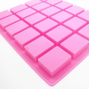 May include: A bright pink silicone mold with a grid pattern of rectangular shapes. The mold is designed for creating multiple small, square-shaped items. The overall design is simple and clean, with a focus on functionality.
